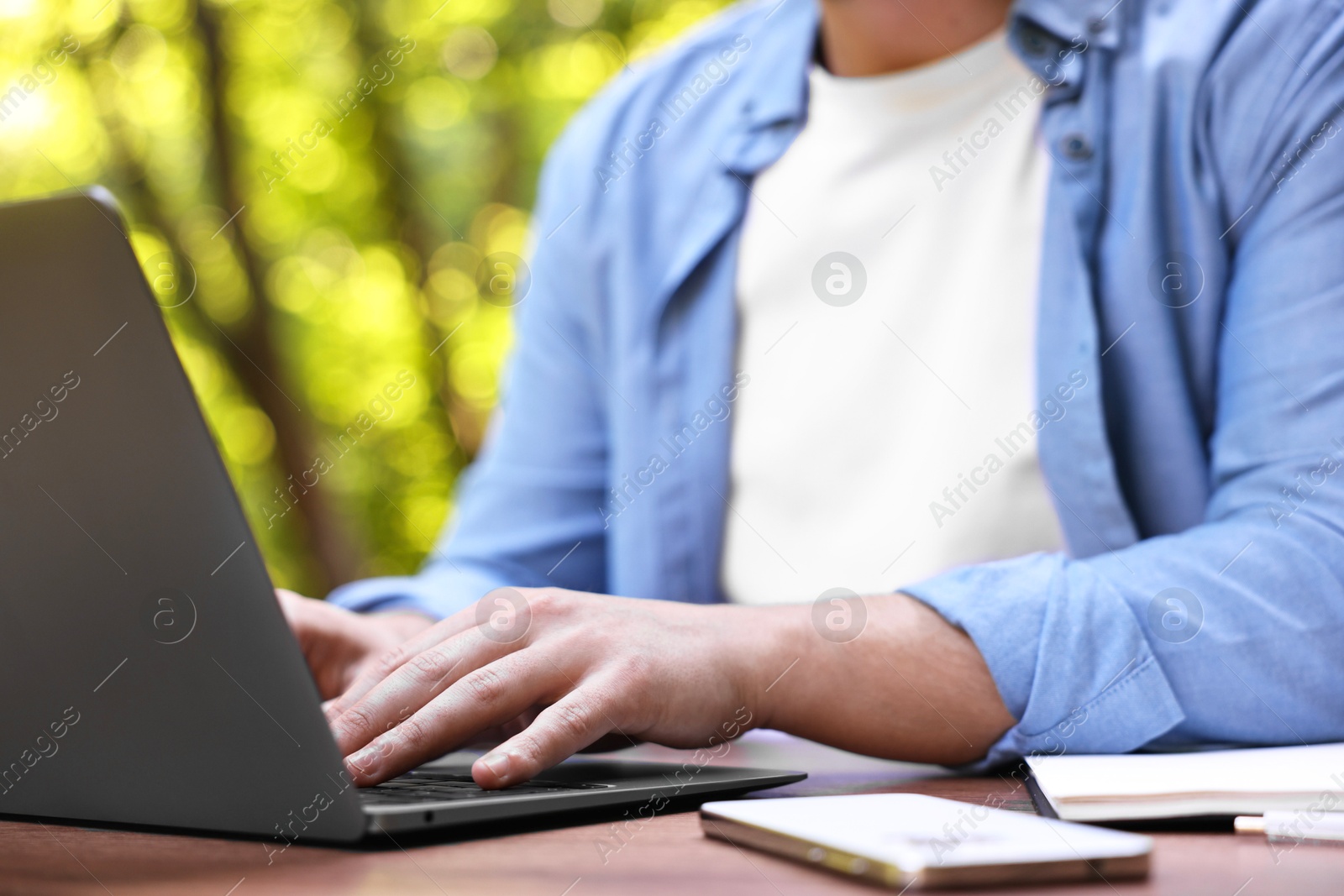 Photo of Freelancer working with laptop at table outdoors, closeup. Remote job