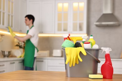 Photo of Professional janitor working in kitchen, focus on bucket with supplies. Cleaning service