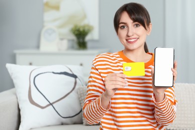 Photo of Woman holding SIM card and smartphone on sofa indoors