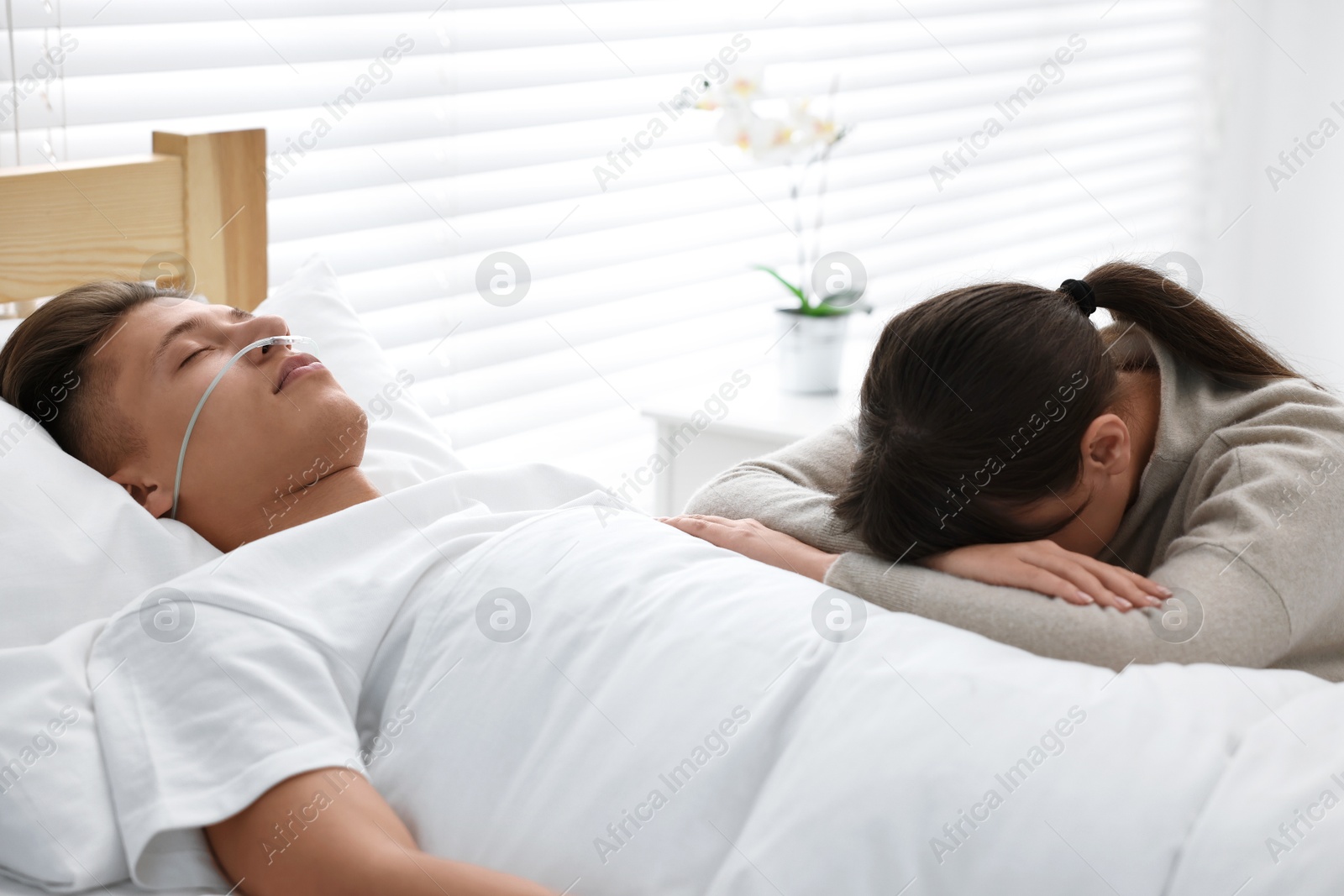 Photo of Coma patient. Sad young woman near her husband in hospital