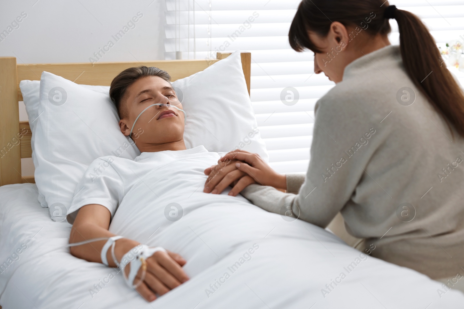 Photo of Coma patient. Sad young woman near her husband in hospital