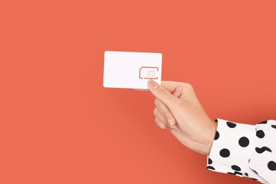 Photo of Woman holding SIM card on terracotta background, closeup