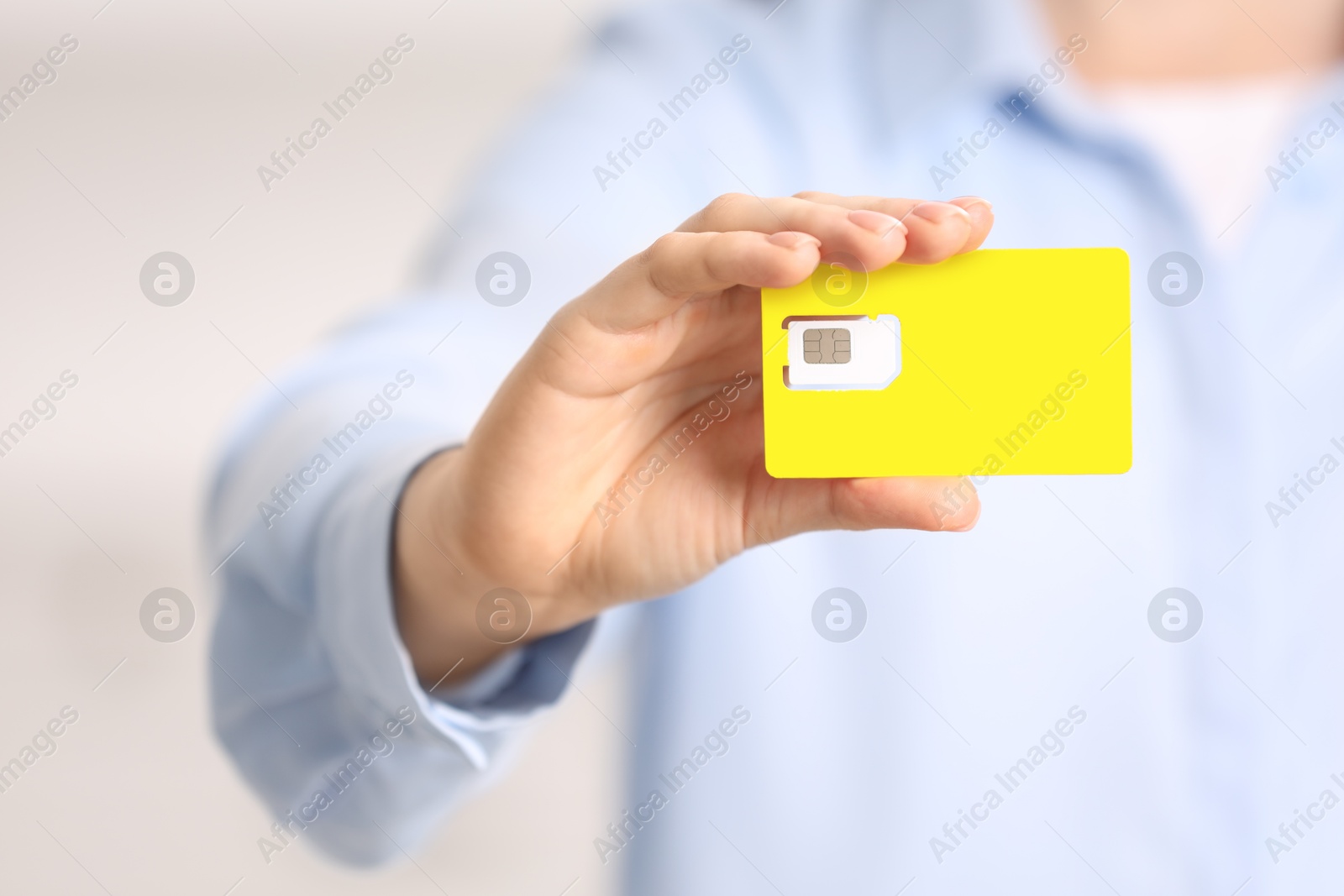 Photo of Woman holding modern SIM card indoors, closeup