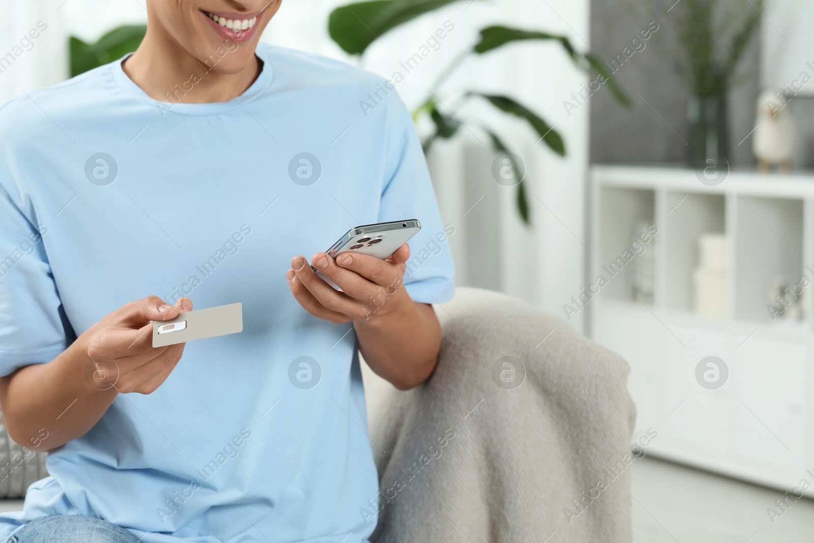 Photo of Man with SIM card and smartphone indoors, closeup