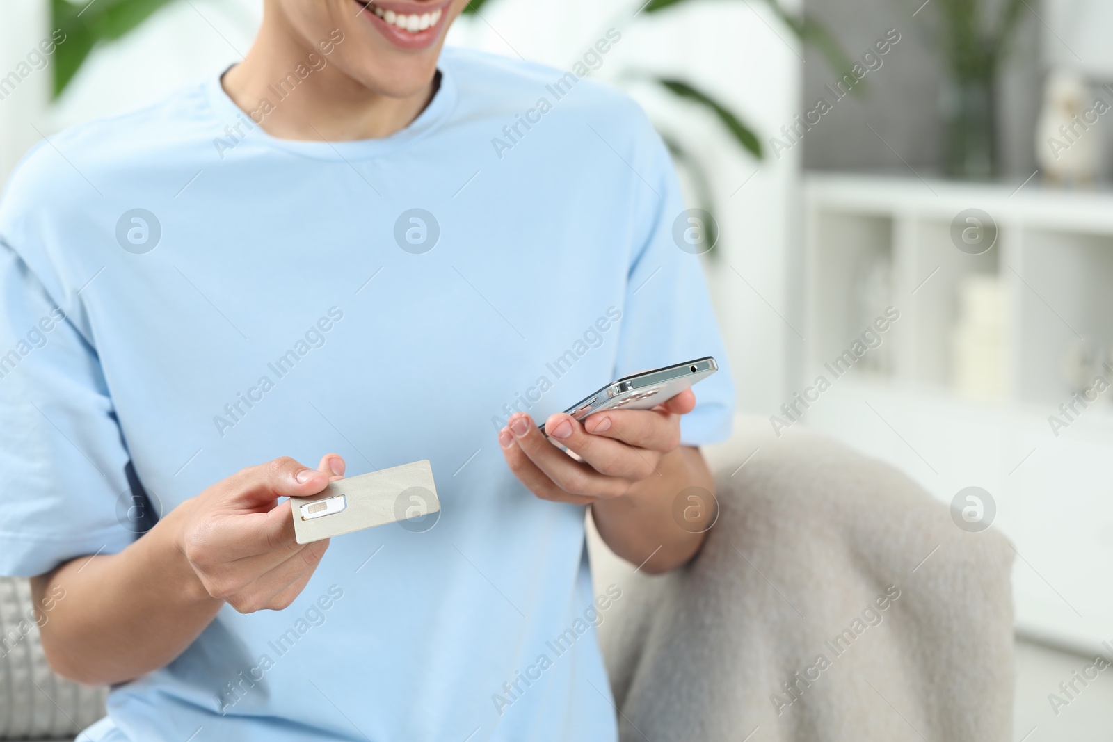 Photo of Man with SIM card and smartphone indoors, closeup