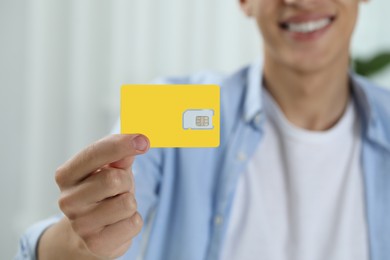 Photo of Man holding SIM card indoors, closeup view