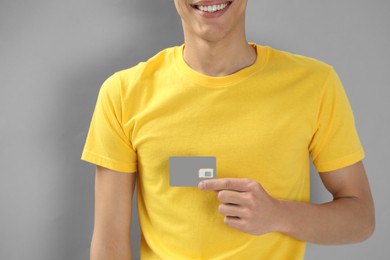 Photo of Man holding SIM card on grey background, closeup