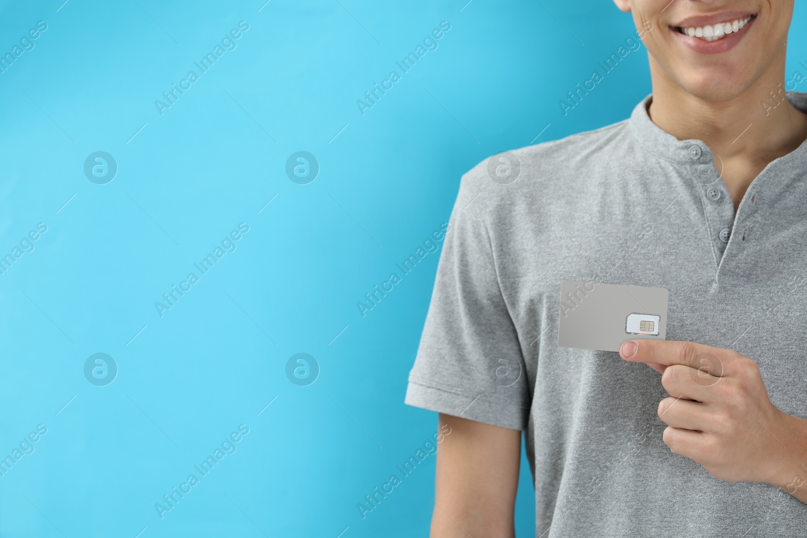 Photo of Man with SIM card on light blue background, closeup. Space for text