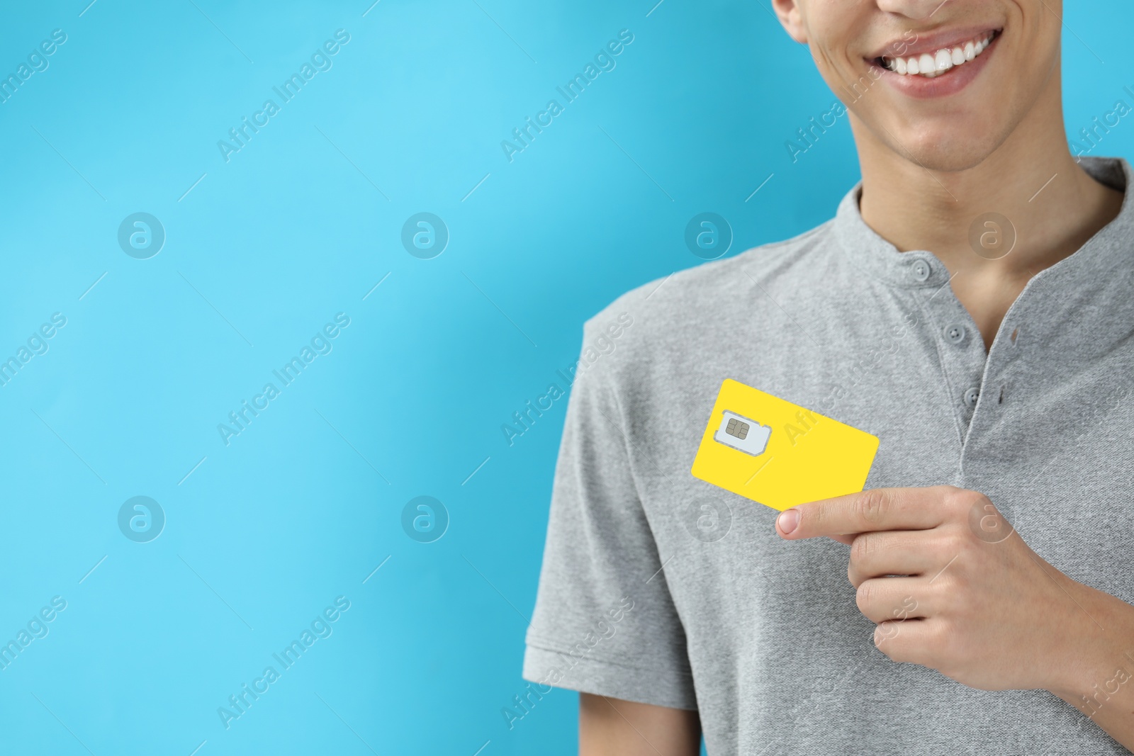 Photo of Man with SIM card on light blue background, closeup. Space for text