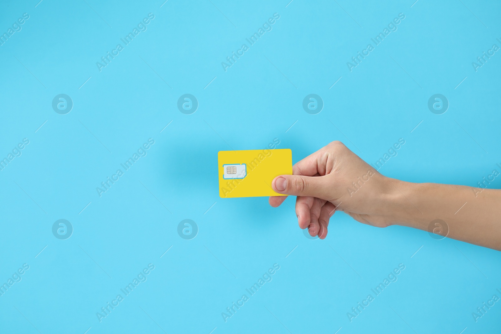 Photo of Man with SIM card on light blue background, closeup