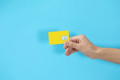 Photo of Man with SIM card on light blue background, closeup