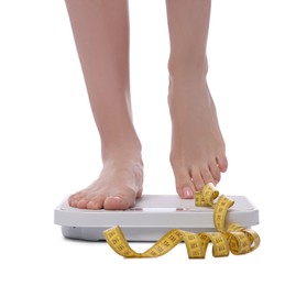 Photo of Diet and weight loss concept. Woman on floor scale and measuring tape against white background, closeup