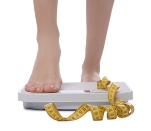 Photo of Diet and weight loss concept. Woman on floor scale and measuring tape against white background, closeup