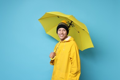 Photo of Young man with yellow umbrella on light blue background