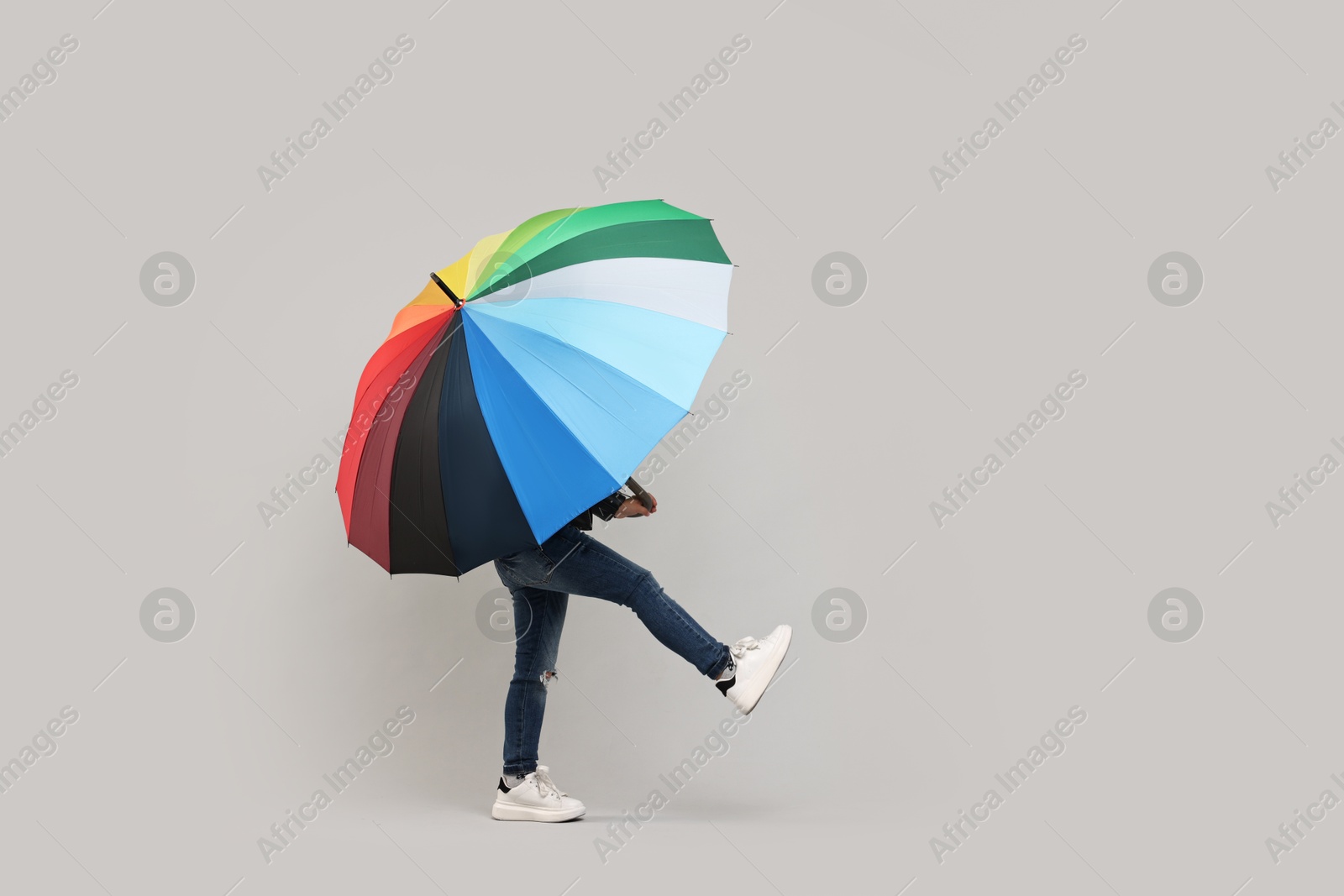 Photo of Little girl with colorful umbrella on light grey background