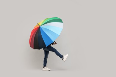 Photo of Little girl with colorful umbrella on light grey background