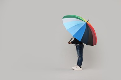 Photo of Little girl with colorful umbrella on light grey background. Space for text