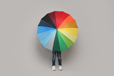 Photo of Little girl with colorful umbrella on light grey background