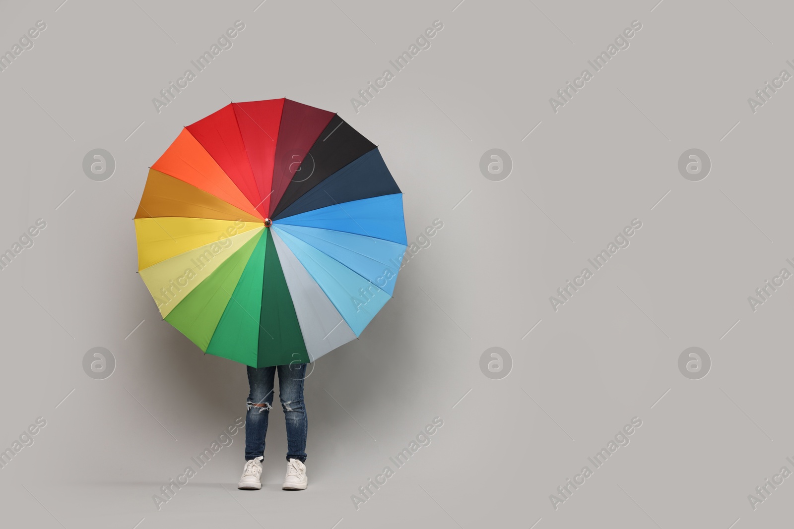 Photo of Little girl with colorful umbrella on light grey background. Space for text