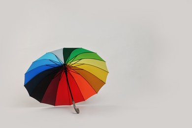 Photo of Stylish colorful umbrella on light grey background. Space for text