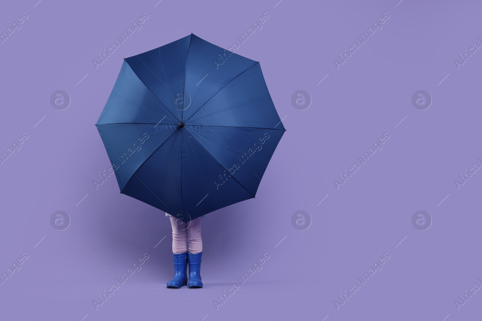 Photo of Little girl with blue umbrella on purple background. Space for text