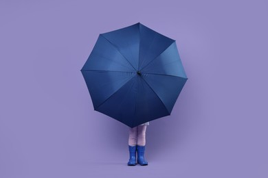 Photo of Little girl with blue umbrella on purple background