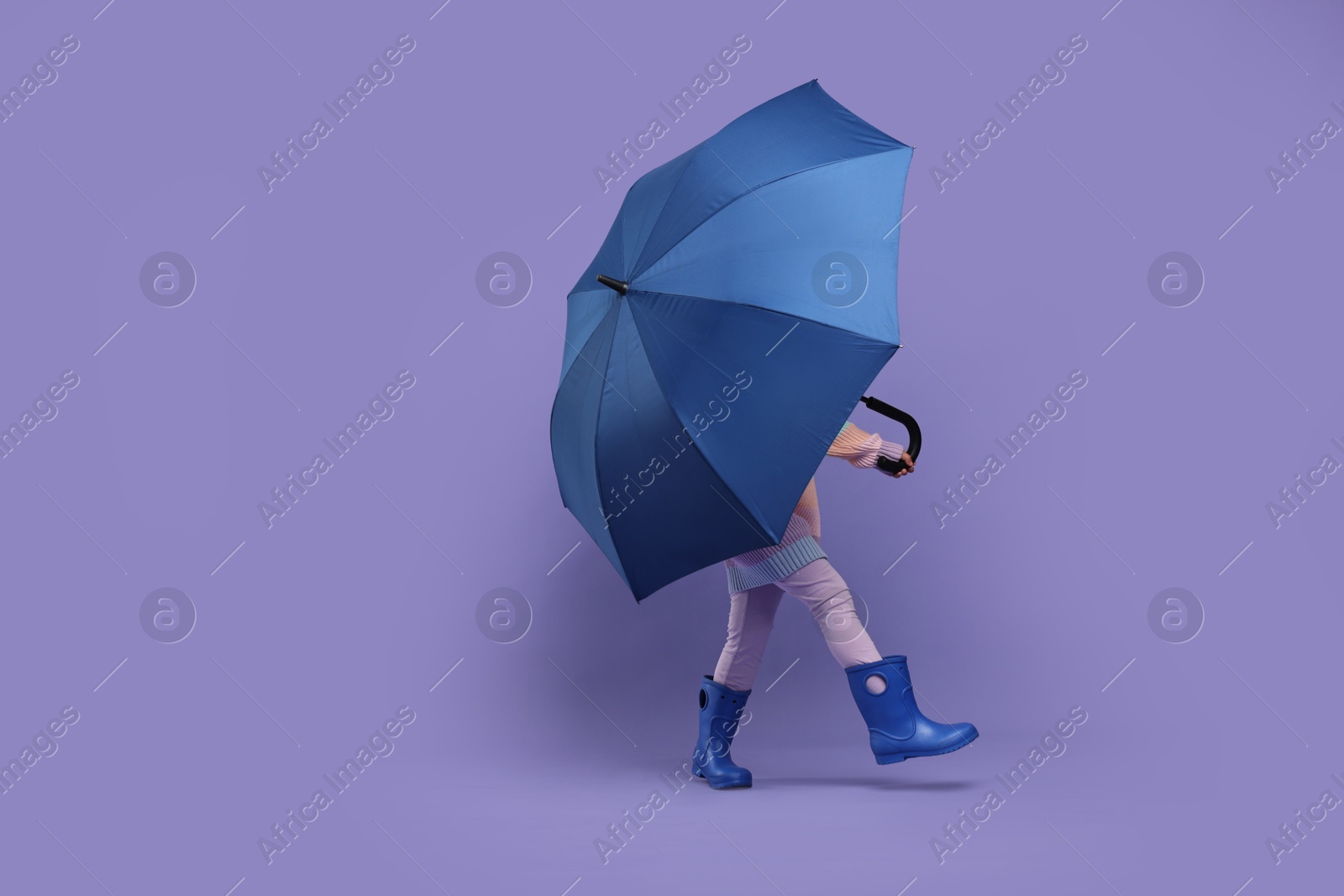 Photo of Little girl with blue umbrella on purple background. Space for text