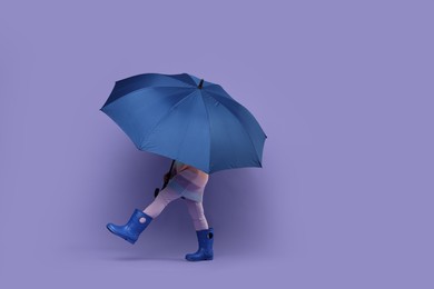 Photo of Little girl with blue umbrella on purple background. Space for text