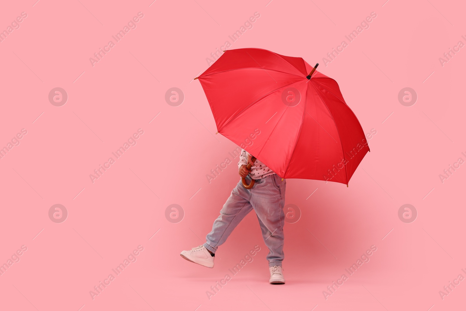 Photo of Little girl with red umbrella on pink background