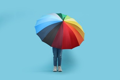 Photo of Little girl with colorful umbrella on light blue background