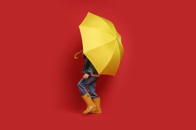 Photo of Little boy with yellow umbrella on red background