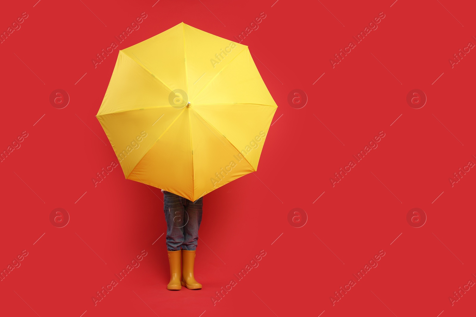 Photo of Little boy with yellow umbrella on red background, space for text