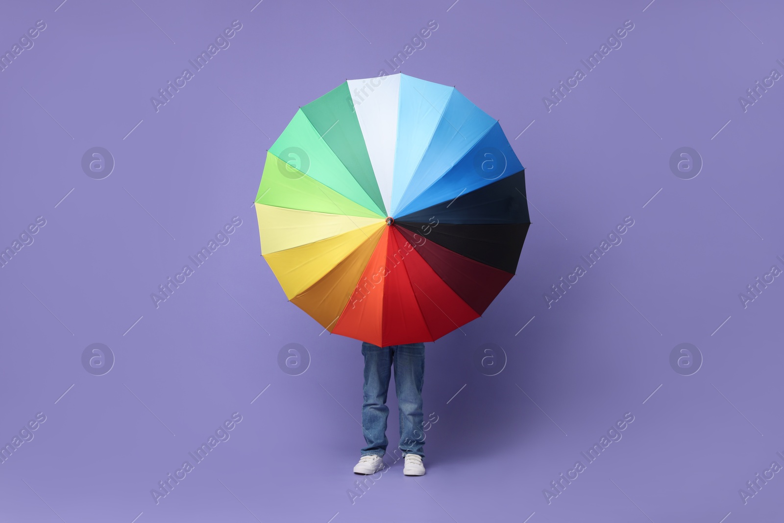 Photo of Little boy with rainbow umbrella on purple background