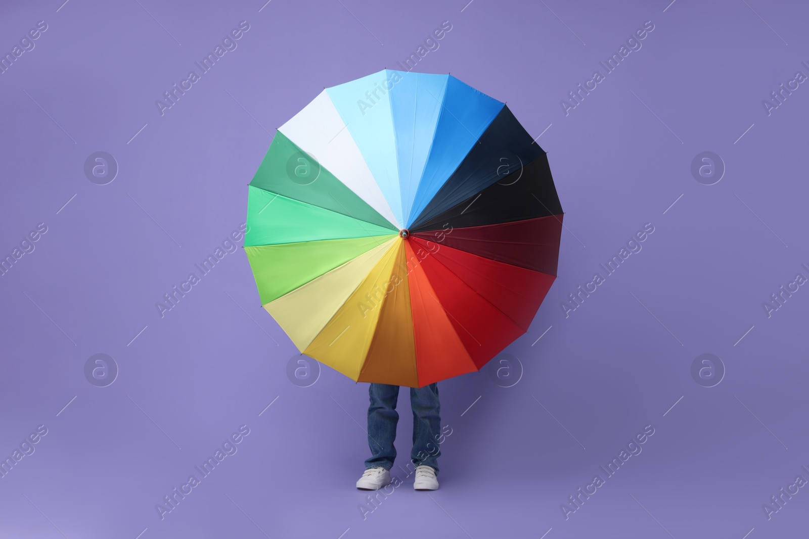 Photo of Little boy with rainbow umbrella on purple background