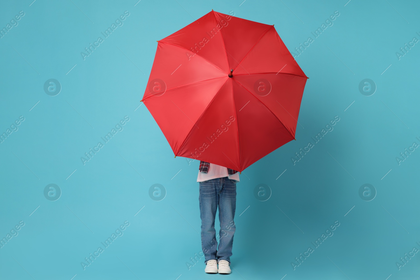 Photo of Little boy with red umbrella on light blue background