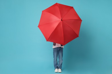 Photo of Little boy with red umbrella on light blue background