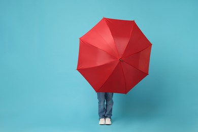 Little boy with red umbrella on light blue background