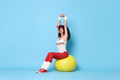 Photo of Aerobics. Happy woman with fitness ball on light blue background