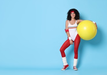 Photo of Aerobics. Happy woman with fitness ball on light blue background, space for text