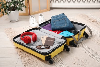 Photo of Open suitcase with traveler's belongings on floor