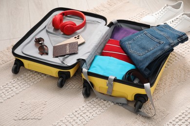 Photo of Open suitcase with traveler's belongings on floor