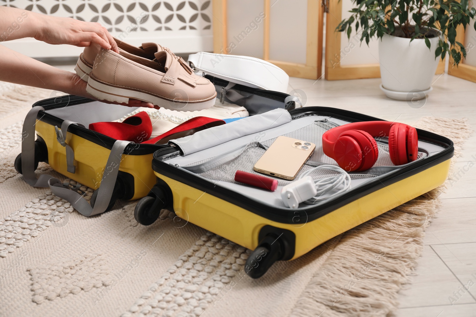 Photo of Woman packing suitcase for trip at home, closeup