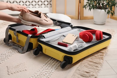 Photo of Woman packing suitcase for trip at home, closeup