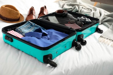 Open suitcase with traveler's belongings on bed, closeup