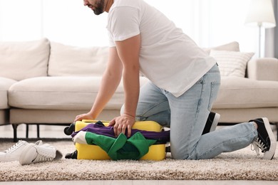 Photo of Man packing suitcase on floor at home, closeup