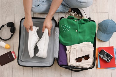 Photo of Man packing suitcase on floor at home, top view