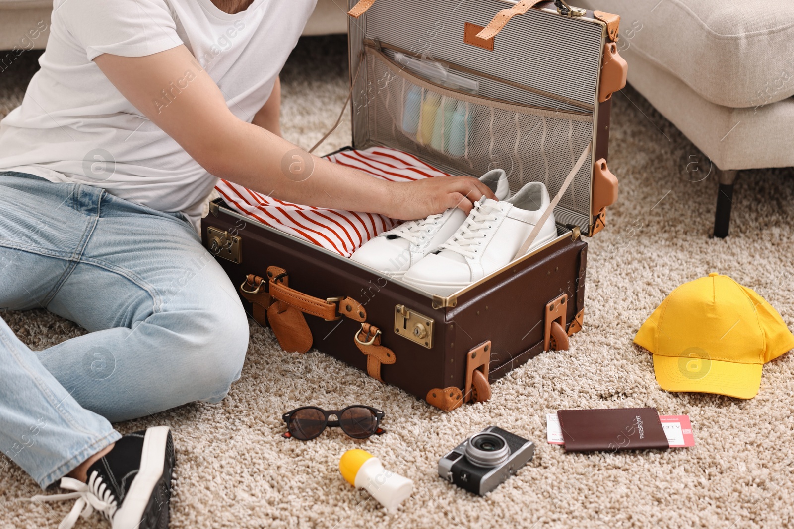 Photo of Man packing suitcase on floor at home, closeup