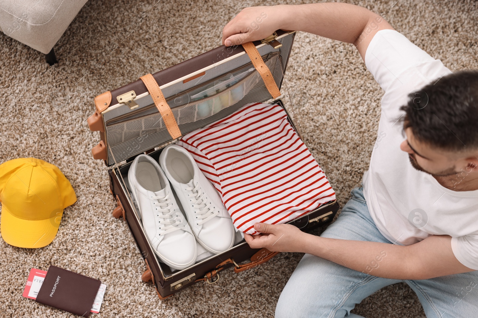 Photo of Man packing suitcase on floor at home, top view