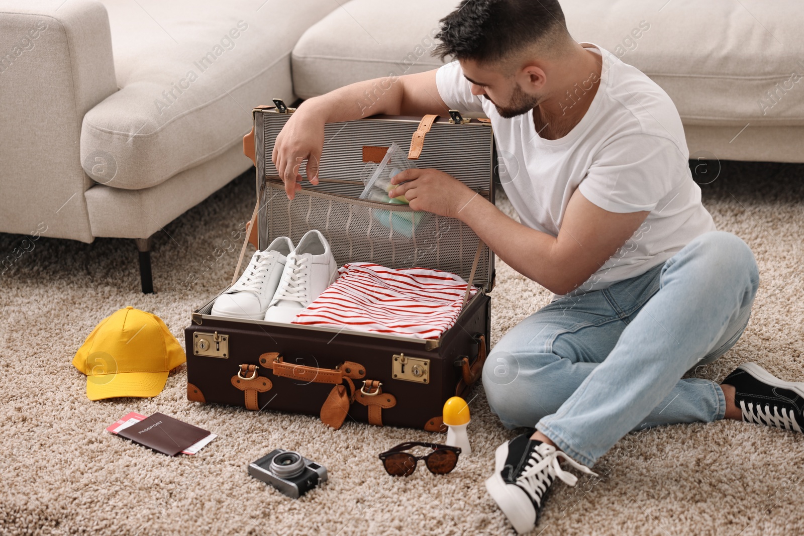 Photo of Man packing suitcase on floor at home