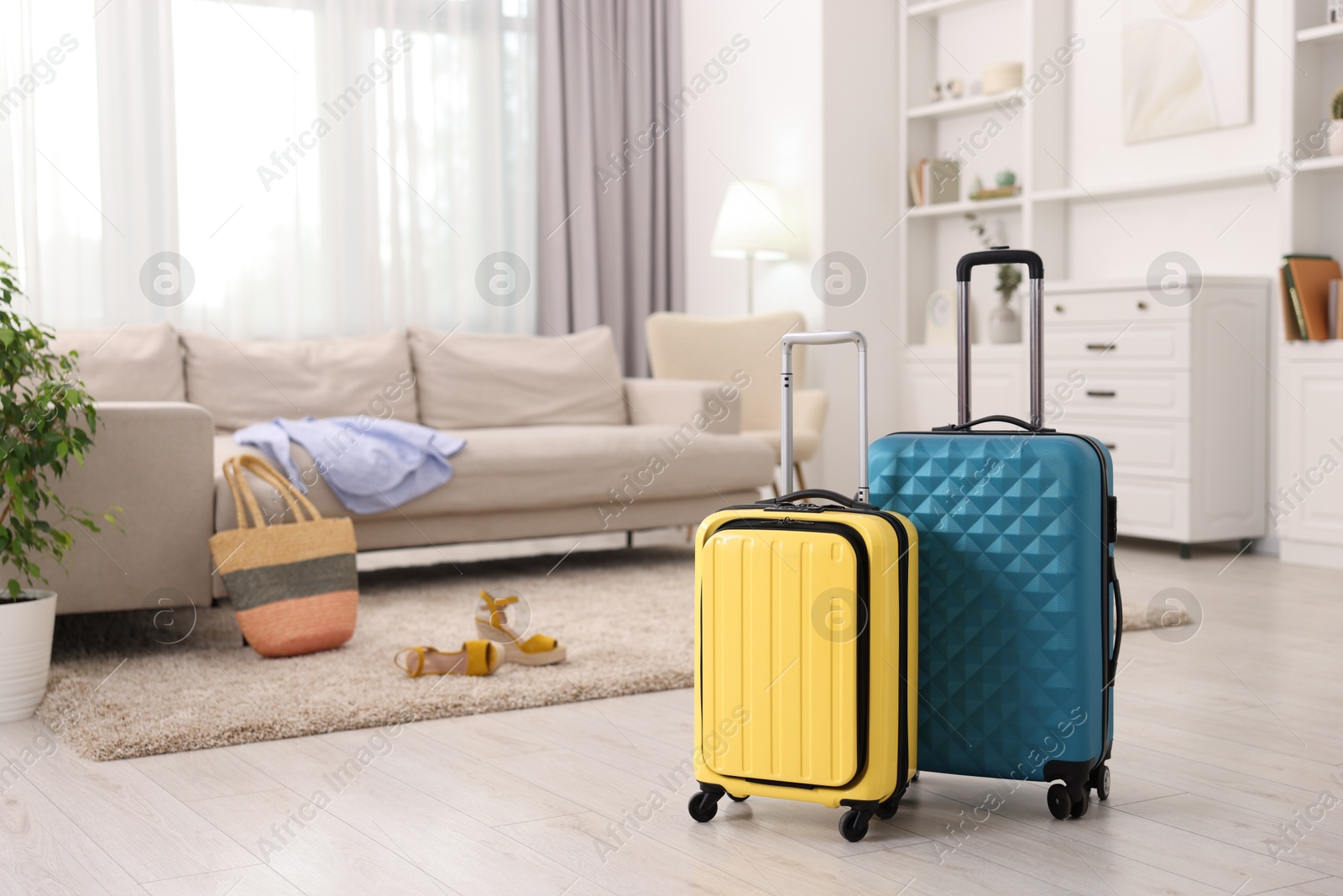 Photo of Two color suitcases on floor at home, space for text